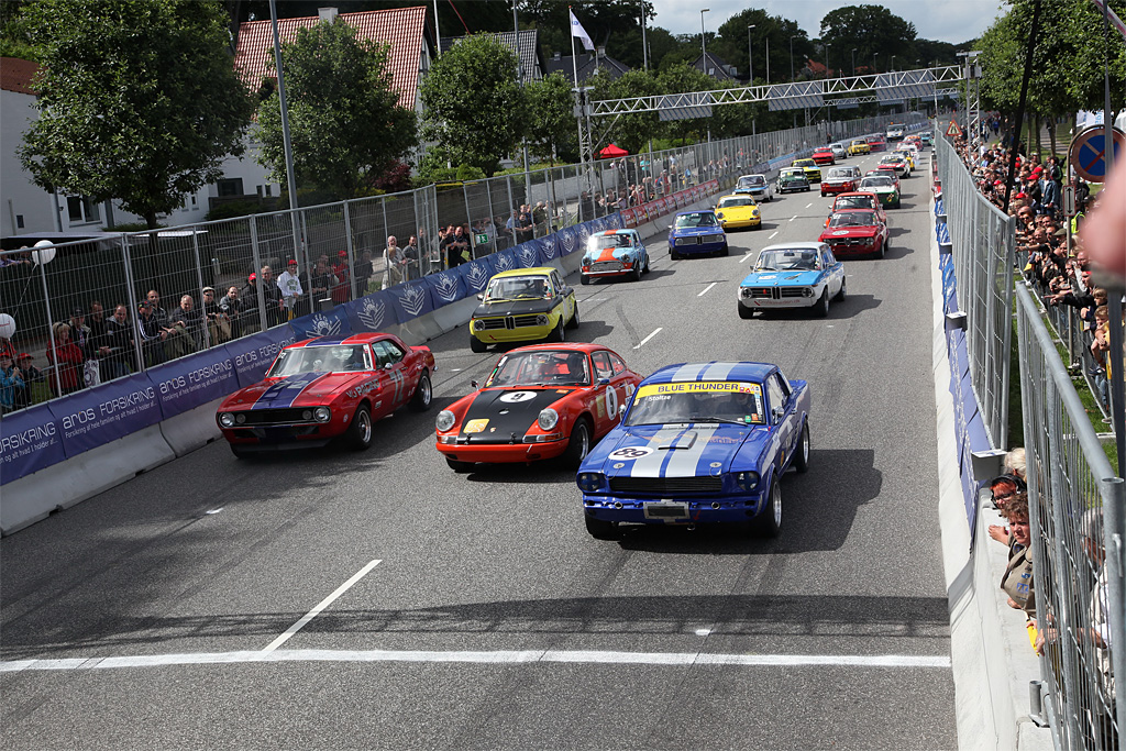 Fra Classic Race Aarhus 2012 i 1971-klassen, ”muskel-bilerne” Chevrolet Camaro yderst til venstre med nr. 72 og Ford Mustang med nr. 89 yderst til højre. I 2013 bliver der også deltagelse af DTC-racerne i form af Chevrolet Camaro og Ford Mustang, der kører ægte race i Aarhus’ gader
(Foto: Mogens Olofsen)